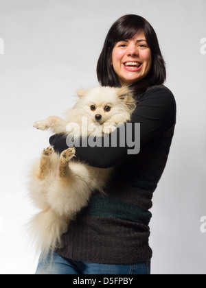 Woman holding small white pomeranian dog Stock Photo