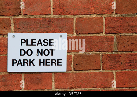 'Please do not park here sign'  screwed to a red brick wall in Horsham Sussex England Stock Photo