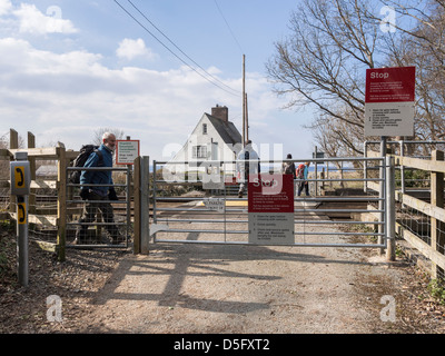 People walking across unmanned level crossing over a railway line at Glan-y-mor Elias near Llanfairfechan Conwy North Wales UK Stock Photo