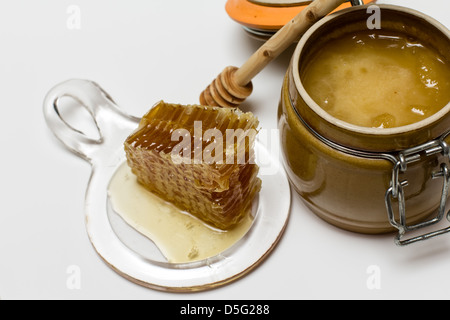Sweet honey in pot with honeycomb and wooden stick Stock Photo