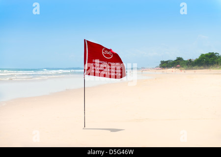 Season of storms. Red flag on the sand beach with no Swimming sign . Stock Photo