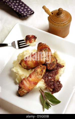 A meal of Lincolnshire sausages wrapped with bacon (pigs in blankets) with mashed potato and onion gravy Stock Photo