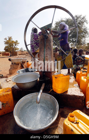 Women turn the wheel of a water pump in a village, Burkina Faso, Africa Stock Photo