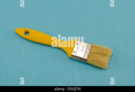 brush 40mm wide with a yellow shaft handle on blue background. paint tool. Stock Photo