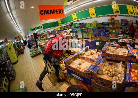 CHEAPER: A middle aged woman shopping for discount cheap affordable fresh vegetables in LIDL discount supermarket, UK Stock Photo