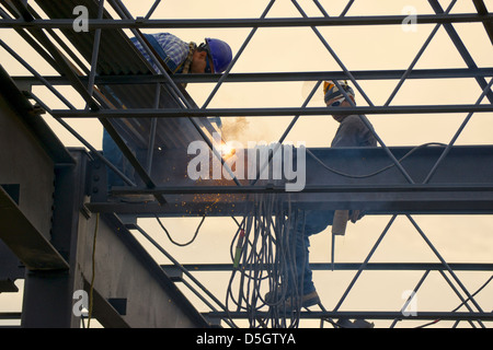 Ironworkers welding the steel framework of a building. One welding one looking on. Stock Photo
