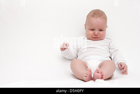 Little baby sitting on bed and cries Stock Photo