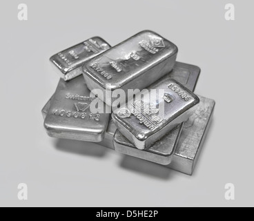 Silver bullion bars in a pile on plain grey background Stock Photo