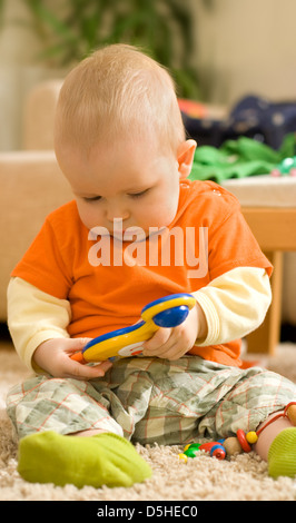 Baby boy sitting and playing - playing with a colorful plastic toy Stock Photo