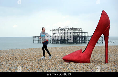 A giant red stiletto shoe caused a stir for early morning runners and passers by on Brighton seafront today when it appeared as part of Churchill Square Shopping Centre's If the Shoe Fits Event which is taking place over the next couple of days. Stock Photo