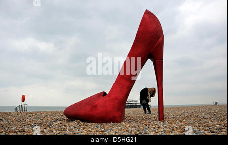 Brighton, Sussex, UK. 3rd April 2013. A giant red stiletto shoe caused a stir for early morning runners and passers by on Brighton seafront today when it appeared as part of Churchill Square Shopping Centre's If the Shoe Fits Event which is taking place over the next couple of days. Stock Photo