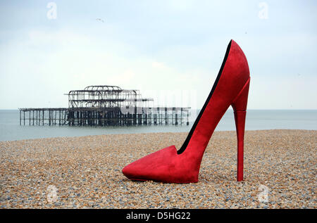 A giant red stiletto shoe caused a stir for early morning runners and passers by on Brighton seafront today UK Stock Photo