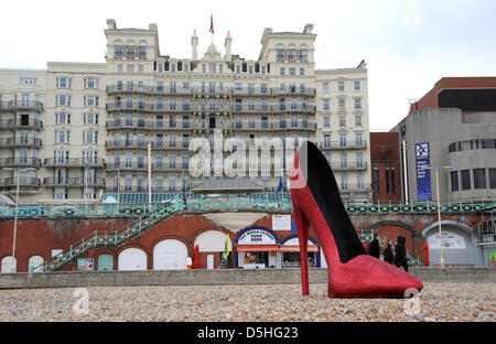 A giant red stiletto shoe caused a stir for early morning runners and passers by on Brighton seafront today Stock Photo