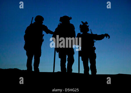 Silhouetted against twilight US Marine Special Operations Team members assist with security during a construction project for an Afghan Local Police checkpoint March 30, 2013 in Helmand province, Afghanistan. Stock Photo