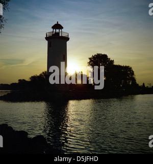 Lighthouse in silhouette with sun setting in the background. Stock Photo