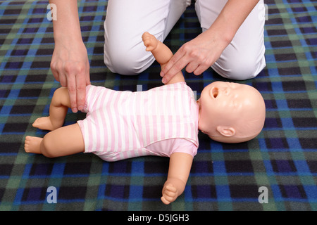 First aid instructor showing how to check pulse on infant dummy Stock Photo