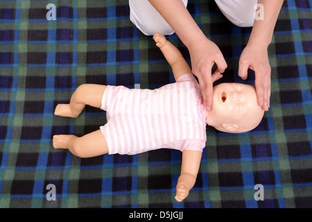 First aid instructor showing how to position infant head before proceeding to mouth-to-mouth resuscitation - view from above Stock Photo