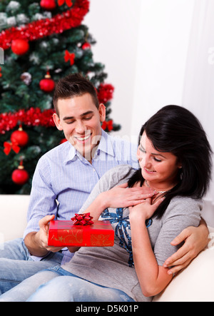 Young man giving a surprise Christmas present to his girlfriend Stock Photo