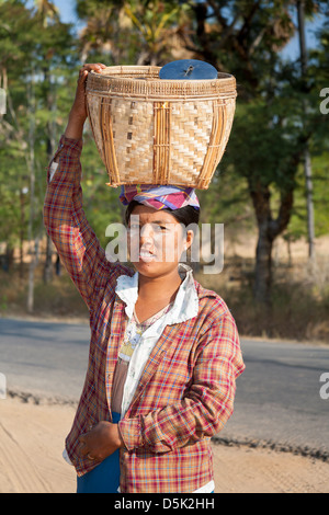 Woman carrying a basket on her head, Kyaukpadaung, near Bagan, Myanmar, (Burma) Stock Photo