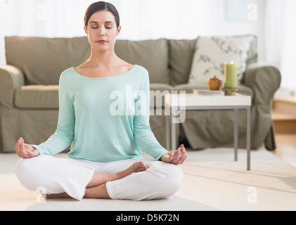 Woman meditating in living room Stock Photo