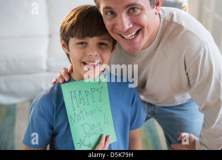 Father and son (8-9) holding Mother's day card Stock Photo