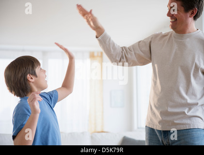 Father and son (8-9) giving each other high five Stock Photo