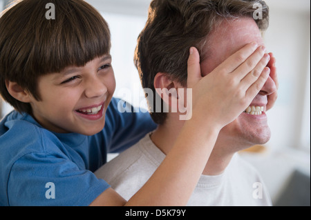 Son (8-9) covering father's eyes Stock Photo