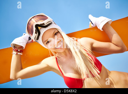 Close-up portrait of a fit girl in bikini holding a snowboard Stock Photo