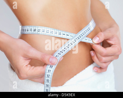 Studio Shot, Woman measuring her waist with tape measure Stock Photo