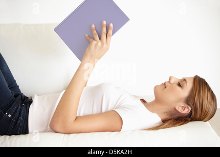 Young woman lying on bed and reading Stock Photo