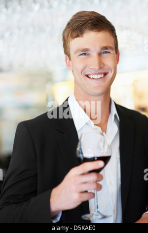 Young handsome man drinking glass of water pointing thumb up to the ...
