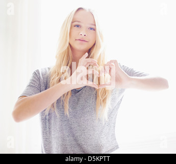 Portrait of teen (16-17) girl making heart shape with hands Stock Photo