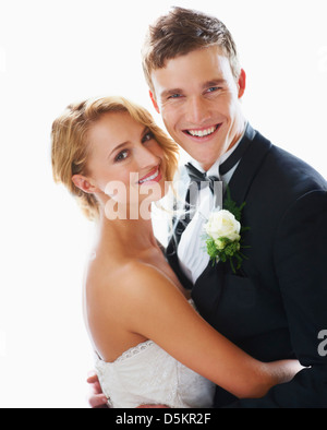 Studio portrait of elegant bride hugging groom sitting on chair Stock