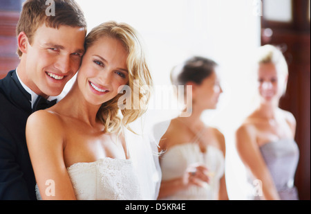 Portrait of newly wed couple, bridesmaids in background Stock Photo