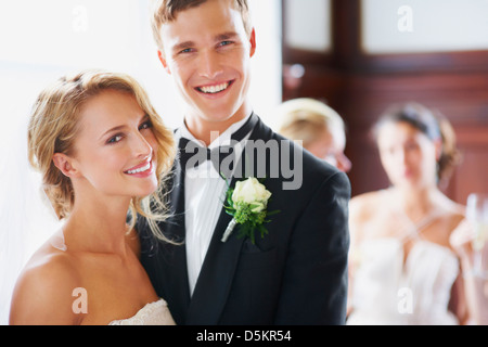 Portrait of newly wed couple, bridesmaids in background Stock Photo