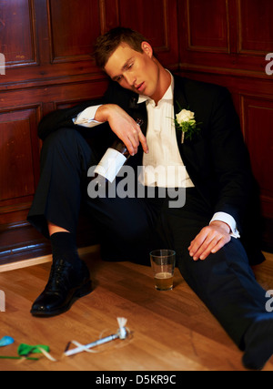 Drunk groom sitting on floor Stock Photo