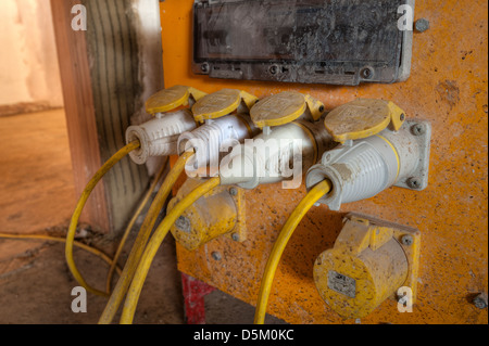 Electrical cables plugs and wires from a heavy duty yellow 110 volt building power supply isolation transformer as DIY project Stock Photo