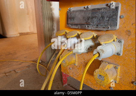 Electrical cables plugs and wires from a heavy duty yellow 110 volt building power supply isolation transformer as DIY project Stock Photo