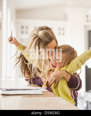 Mother kissing daughter (6-7) during doing homework Stock Photo