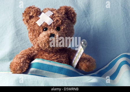 bear in bed with thermometer and plaster Stock Photo