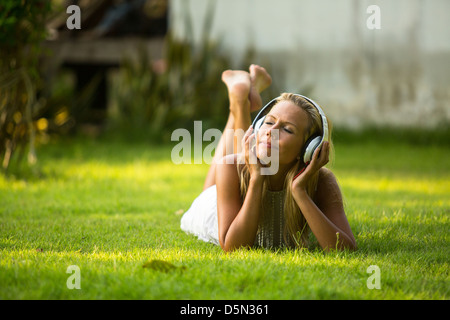 Emotional a lovely girl with headphones enjoying nature and music at sunny day. Stock Photo