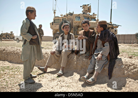 Afghan children watch US Marine Special Operations soldiers during the construction of a new checkpoint by Afghan and US forces April 3, 2013 in the district of Spin Boldak, Kandahar province, Afghanistan. Stock Photo