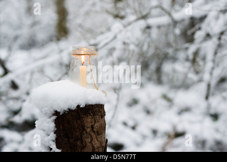 Christmas candle in a glass jar in a snow covered wood Stock Photo