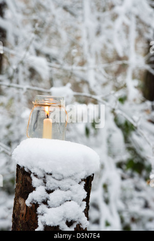 Christmas candle in a glass jar in a snow covered wood Stock Photo