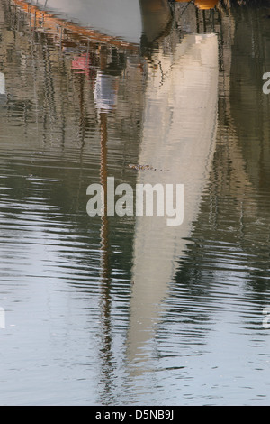 Reflections in Porthmadog harbour of a boat and its sails Stock Photo