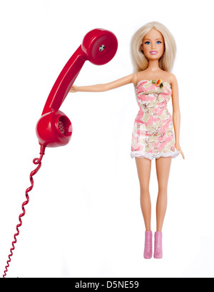 Barbie doll, holding a red phone receiver. Isolated on white. Stock Photo