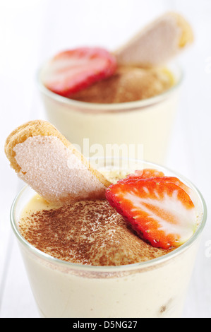 Traditional italian dessert tiramisu in a glass with strawberry on wooden background Stock Photo