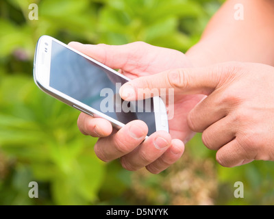 Man hand touching screen on modern mobile smart phone on natural green background Stock Photo