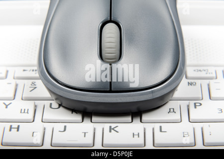 A wireless mouse placed on laptop keyboard Stock Photo