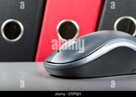 A wireless mouse placed on notebook and three folders in the background Stock Photo